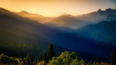 Dark mountains with sunrise in the background and trees in the foreground